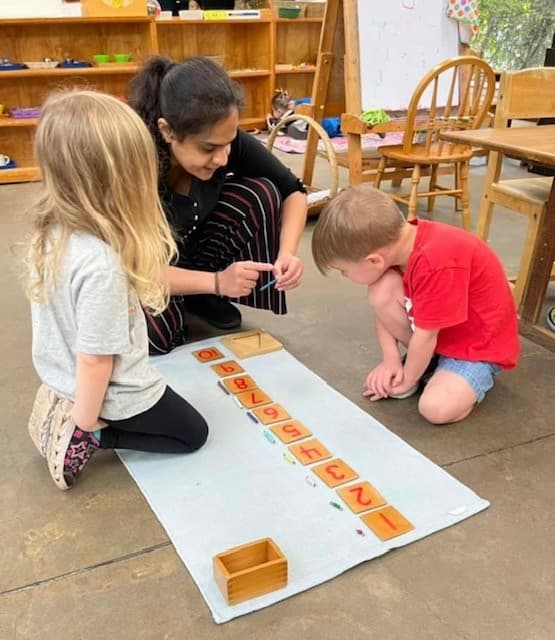 Teacher working with children on a math puzzle activity, demonstrating hands-on learning approach